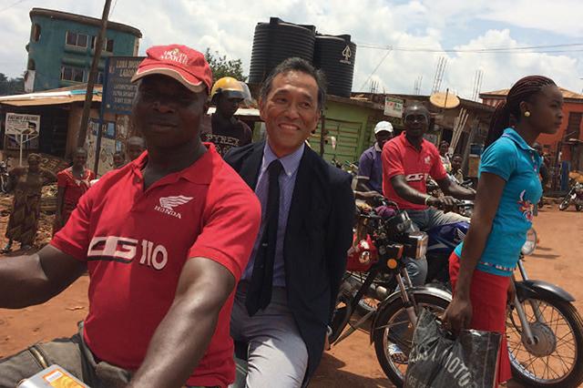 <center>ナイジェリアでバイクタクシーのリヤシートにまたがる室岡社長（2016年）</center>