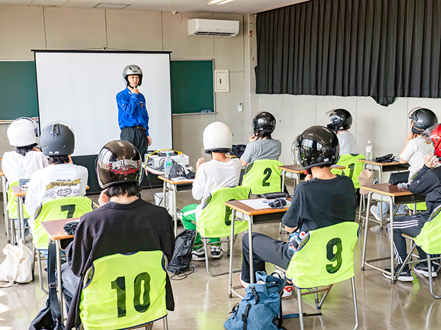講師は(株)早坂サイクル商会のスタッフ2名が担当。原付講習の流れやヘルメットの着用方法について説明